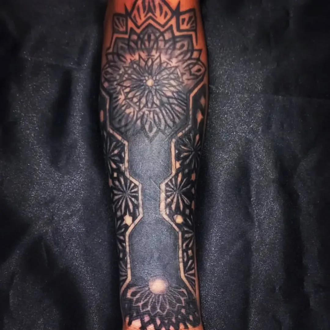 Mandalas y geometría en negro sólido cubriendo el brazo completo