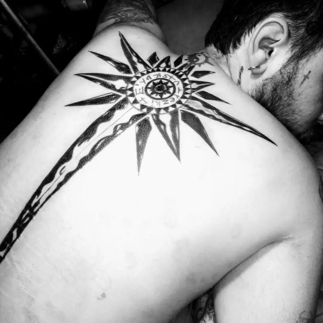 Sol de puntas largas en negro sólido tatuado en la espalda