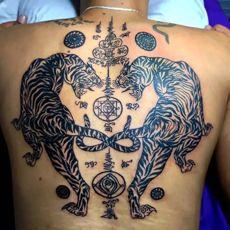 Dos tigres simétricos en blackwork con símbolos, tatuados en la espalda