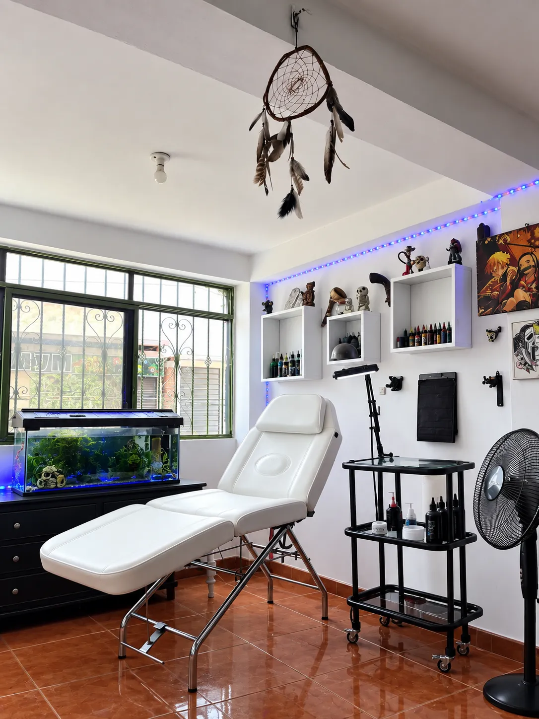 Interior del estudio de Jhonny Tatto en Cali: camilla blanca, carrito de tintas y pared con figuras