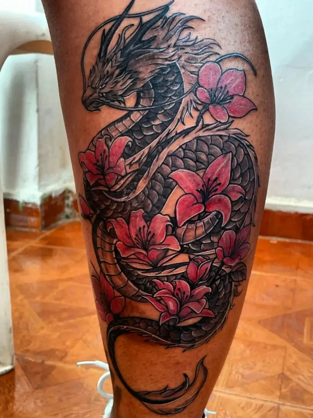 Dragón japonés en negro rodeado de flores rojas de loto