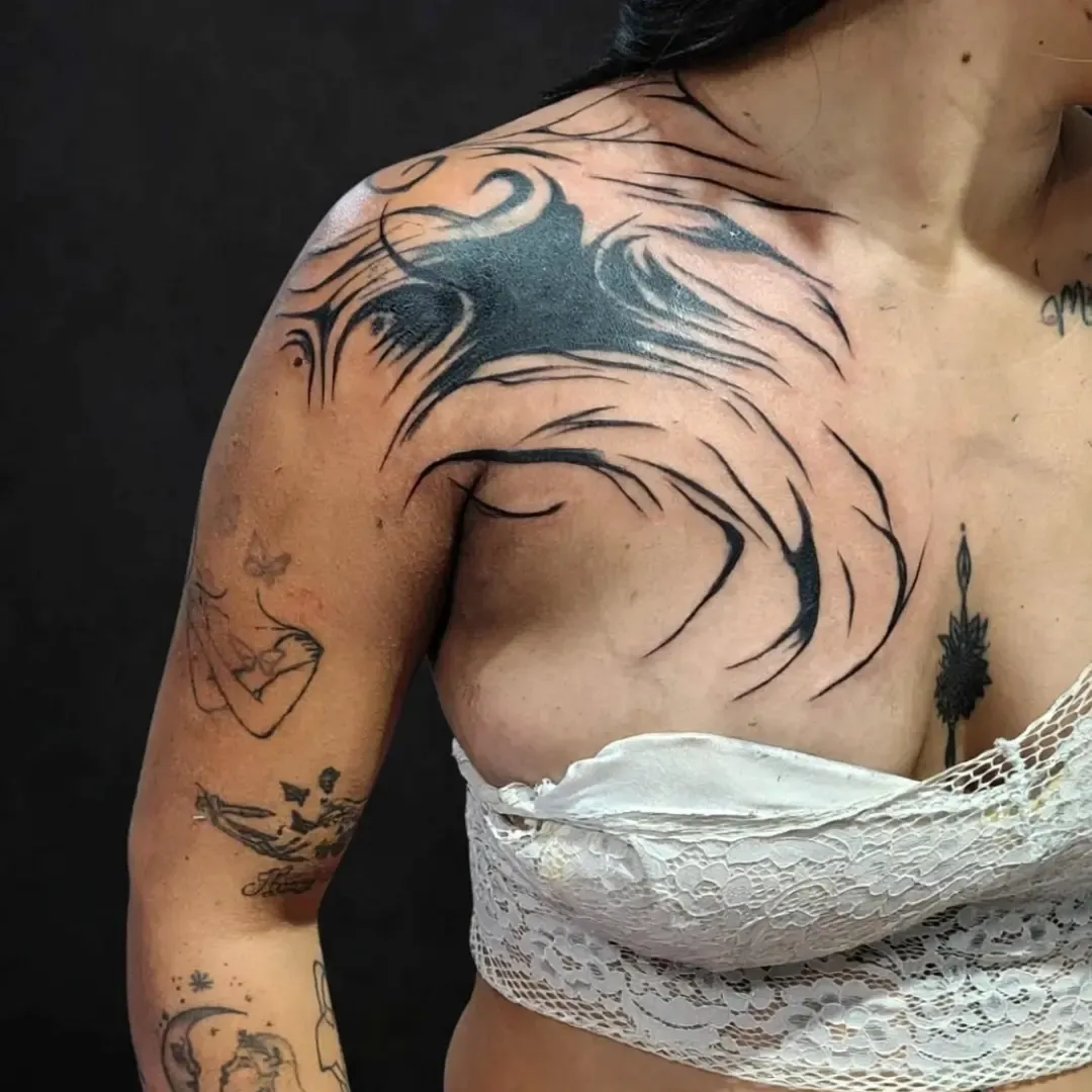 Pieza neotribal en hombro y pecho con trazos que se abren como plumas