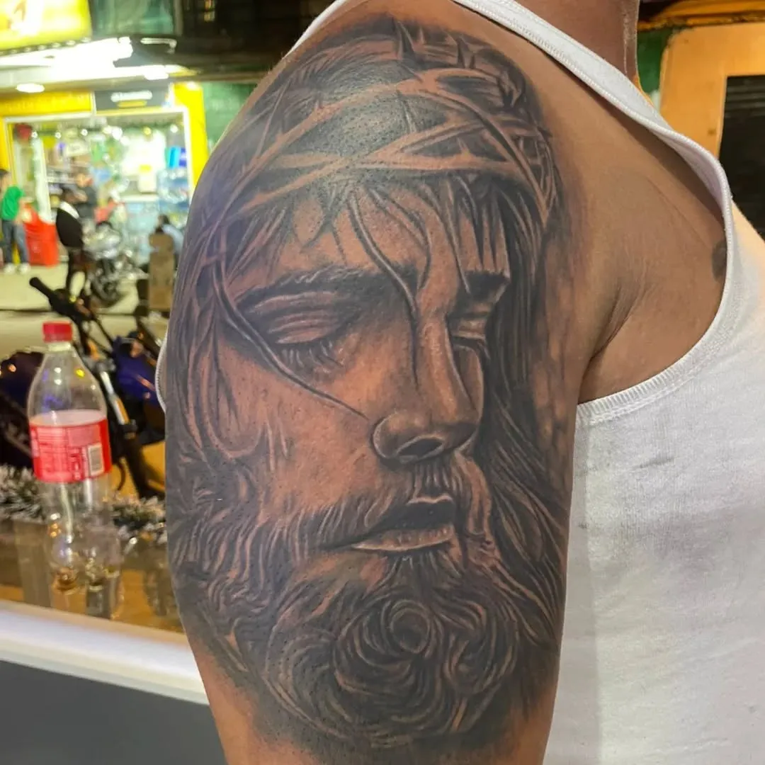 Rostro de Cristo tatuado con realismo en negro y gris