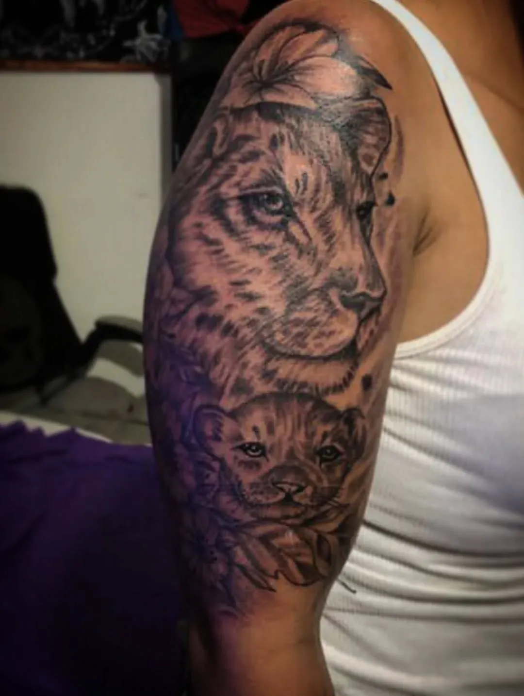 Leona con su cachorro tatuados con realismo en negro y gris
