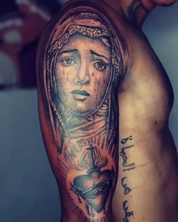 Virgen con lágrimas tatuada con realismo en negro y gris